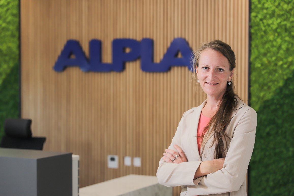 Theresia Gollner in front of the ALPLA logo.