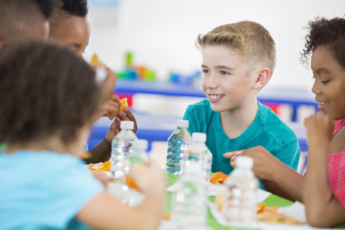 School kids sitting at a table with PET bottles