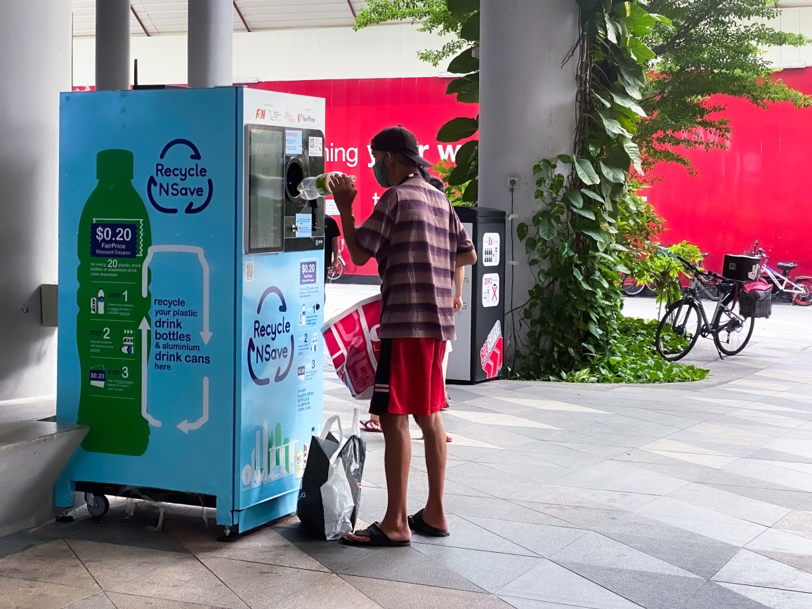 Man in Singapur is throwing a bottle into a deposit system.