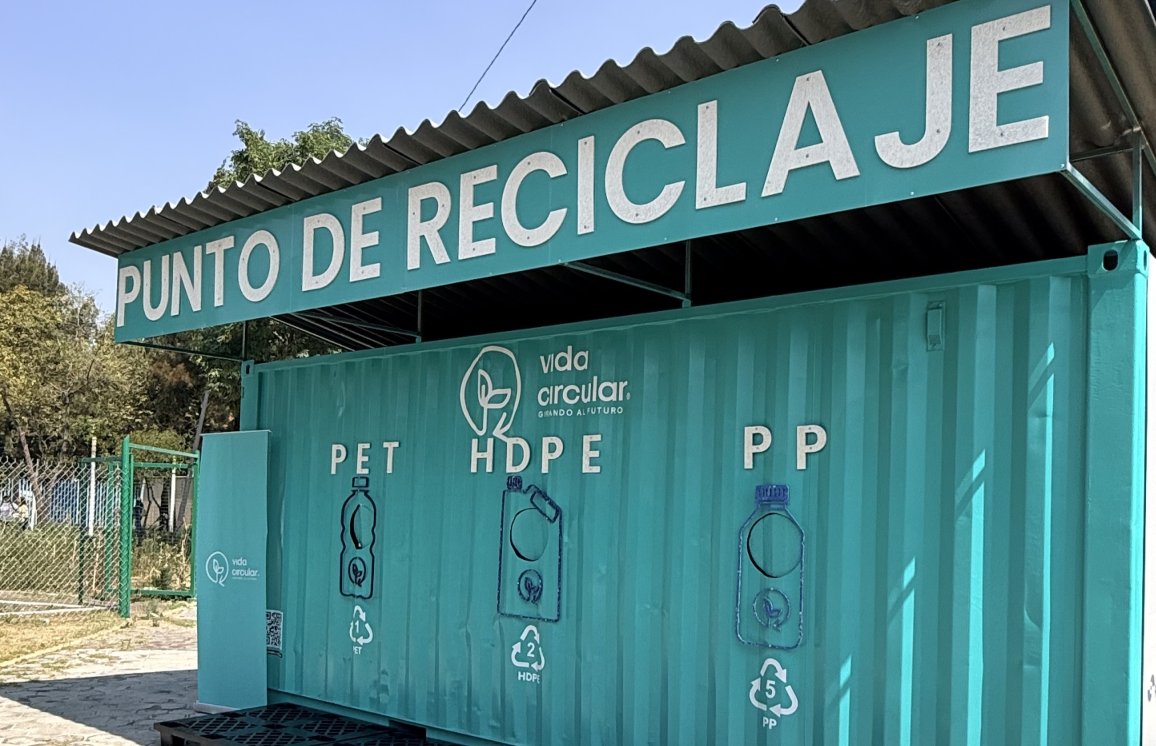 Recyclingstation im Freien mit beschrifteten Behältern für PET-, HDPE- und PP-Kunststoffe.