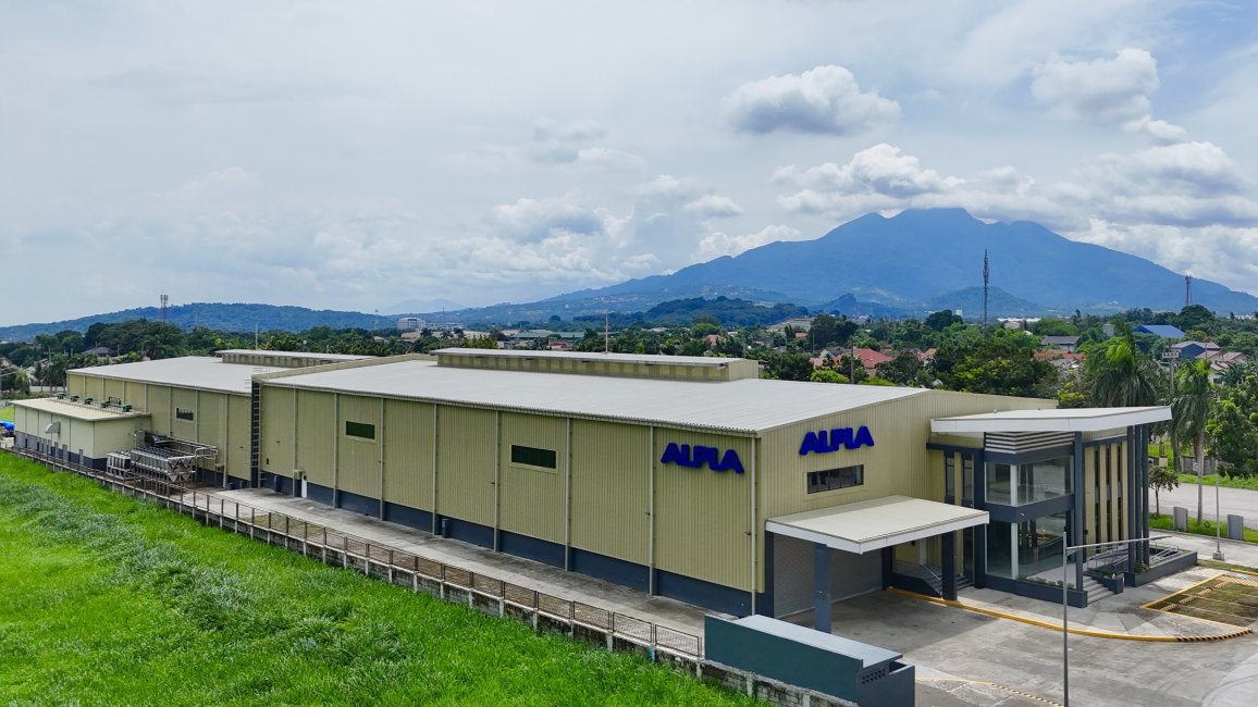 Modern ALPLA factory building in Calamba with mountain backdrop and green landscape.