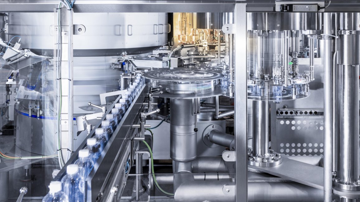 Automated assembly line filling clear plastic bottles in a modern factory setting.