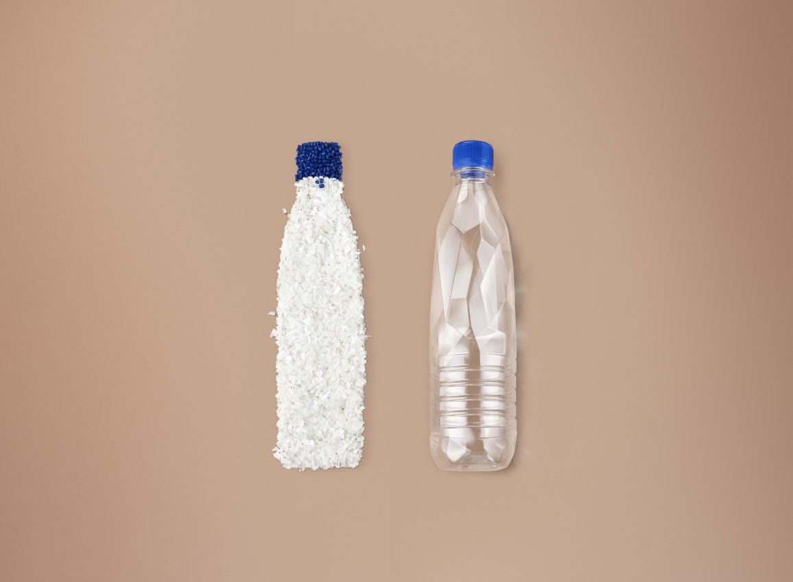 Plastic bottle filled with white resin pellets beside an empty clear plastic bottle, blue caps on both.