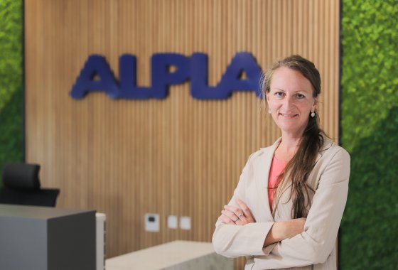 Theresia Gollner in front of the ALPLA logo.