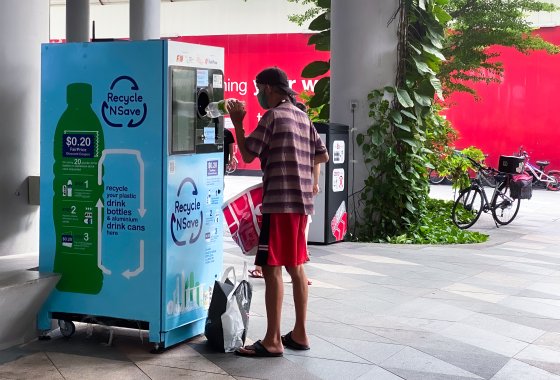 Man in Singapur is throwing a bottle into a deposit system.