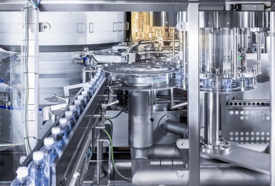 Automated assembly line filling clear plastic bottles in a modern factory setting.